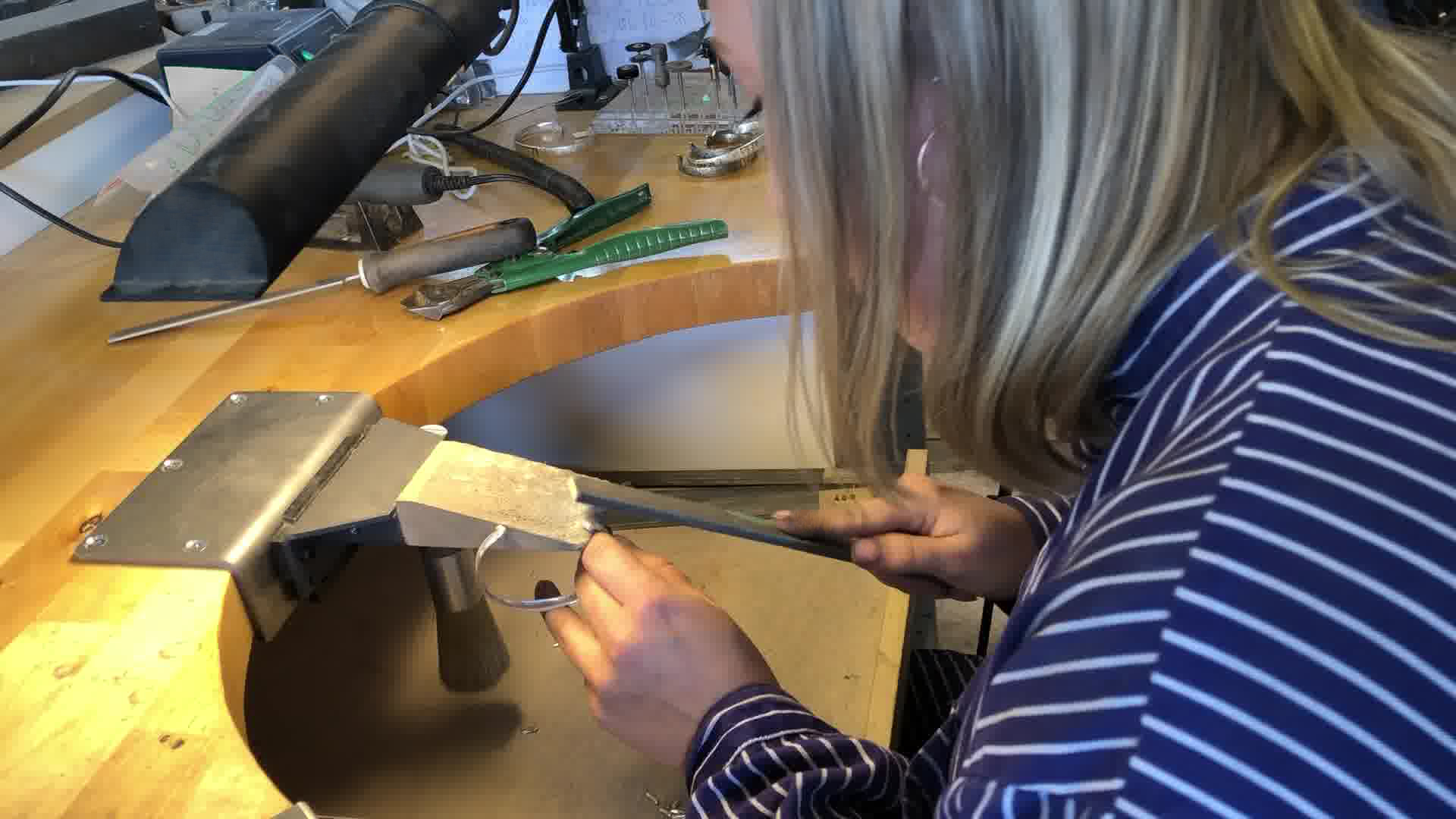 Sabine filing a bracelet by hand at the Foundry